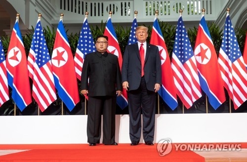 U.S. President Donald Trump (R) poses with North Korean leader Kim Jong-un at the Capella Hotel in Singapore on June 12, 2018, during their summit there, in this photo captured from the Twitter account of White House social media director Dan Scavino. (Yonhap)