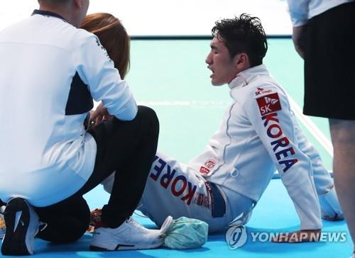 South Korean fencer Park Sang-young writhes in pain while getting his left knee treated after losing to Dmitriy Alexanin of Kazakhstan in the men's individual epee final at the 18th Asian Games at Jakarta Convention Center (JCC) Cendrawashi Hall in Jakarta on Aug. 19, 2018. (Yonhap)