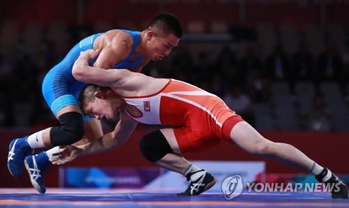 North Korean freestyle wrestler Kang Kum-song (R) competes against Bekhbayar Erdenebat of Mongolia in the men's 57 kilogram division final at the 18th Asian Games at Jakarta Convention Center in Jakarta on Aug. 19, 2018. (Yonhap)
