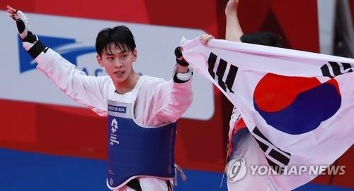 South Korean taekwondo fighter Kim Tae-hun celebrates with the national flag after winning a gold medal in the men's 58-kilogram taekwondo "kyorugi" (sparring) competition at the 18th Asian Games in Jakarta on Aug. 20, 2018. (Yonhap)