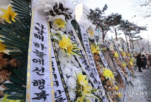 A row of funeral wreaths made of white and yellow flowers is laid alongside the wall of the Seoul Southern District Court on Jan. 13, 2021. (Yonhap)