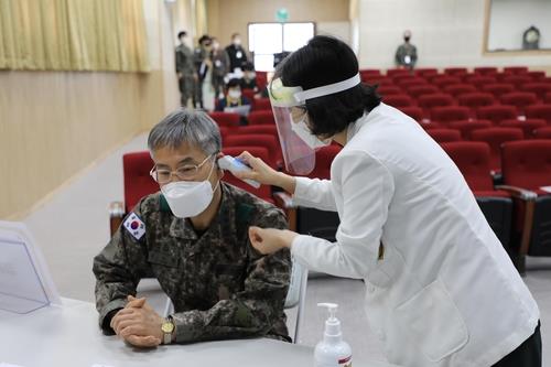 Col. Kim In-young (L), who is the chief of the Korean Armed Forces Yangju Hospital in Gyeonggi Province, has his temperature checked ahead of receiving the COVID-19 vaccine on March 3, 2021, in this photo provided by the defense ministry. (PHOTO NOT FOR SALE) (Yonhap)