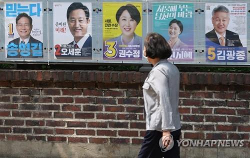 In this file photo, a person looks at posters of Seoul mayor candidates in the June 1 local elections on May 19, 2022. (Yonhap)