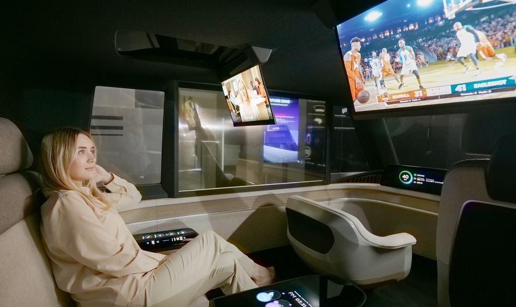The photo provided by LG Display Co. on Jan. 5, 2023, shows a passenger watching a sports program on a rollable panel inside the company's autonomous concept car. (PHOTO NOT FOR SALE) (Yonhap)