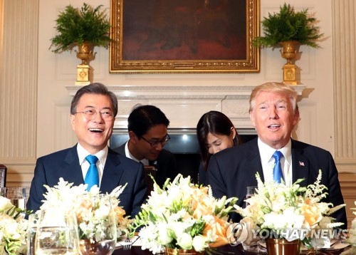 ホワイトハウスで開かれた夕食会で、明るい表情で会話する文大統領とトランプ大統領＝３０日、ワシントン（聯合ニュース）