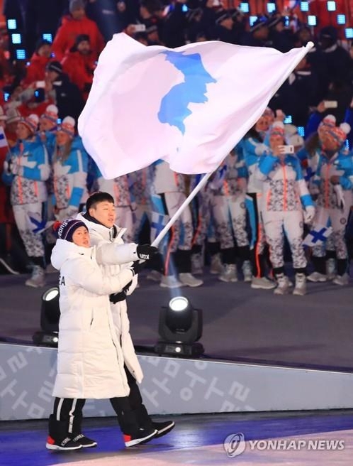 韓国のボブスレー男子のウォン・ユンジョンと北朝鮮アイスホッケー女子のファン・チュングムが朝鮮半島旗を掲げて入場行進を行った＝９日、平昌（聯合ニュース）