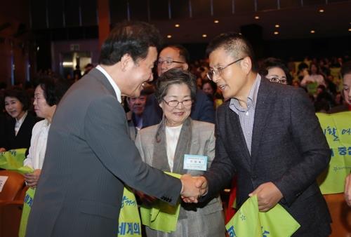 １０月３１日にソウル市内で開かれた全国女性大会で握手を交わす李氏（左）と黄氏＝（聯合ニュース）