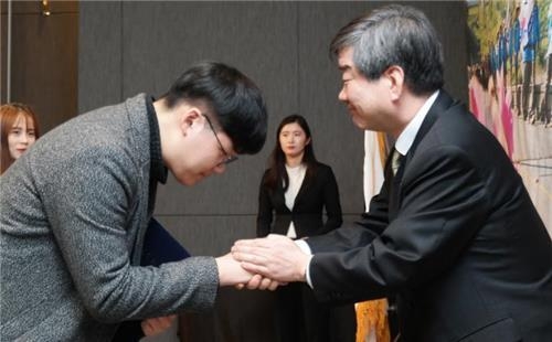 장학증서를 받은 대학생과 악수하는 최평규 S&T그룹 회장.(오른쪽)