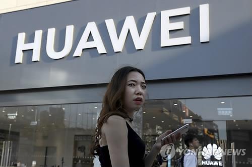 지난 20일(현지시간) 중국 베이징의 화웨이 매장 밖에서 한 여성이 스마트폰을 사용하고 있다. [AP=연합뉴스 자료사진] 