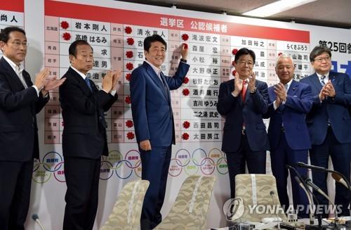 참의원 선거 당선자 이름에 장미 꽃을 붙이는 아베 총리