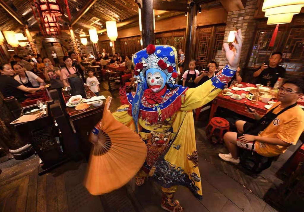 Customers enjoying Chengdu hot pot while watching "bianlian" face-changing act of Sichuan opera