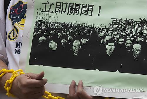지난해 9월 2일 홍콩의 한 경찰서 밖에서 중국 당국의 신장 위구르에서의 인권탄압에 대해 항의하는 시위 도중 한 참가자가 위구르의 수용·구금 실상을 보여주는 사진을 들고 있는 모습. [홍콩 EPA=연합뉴스 자료사진] 