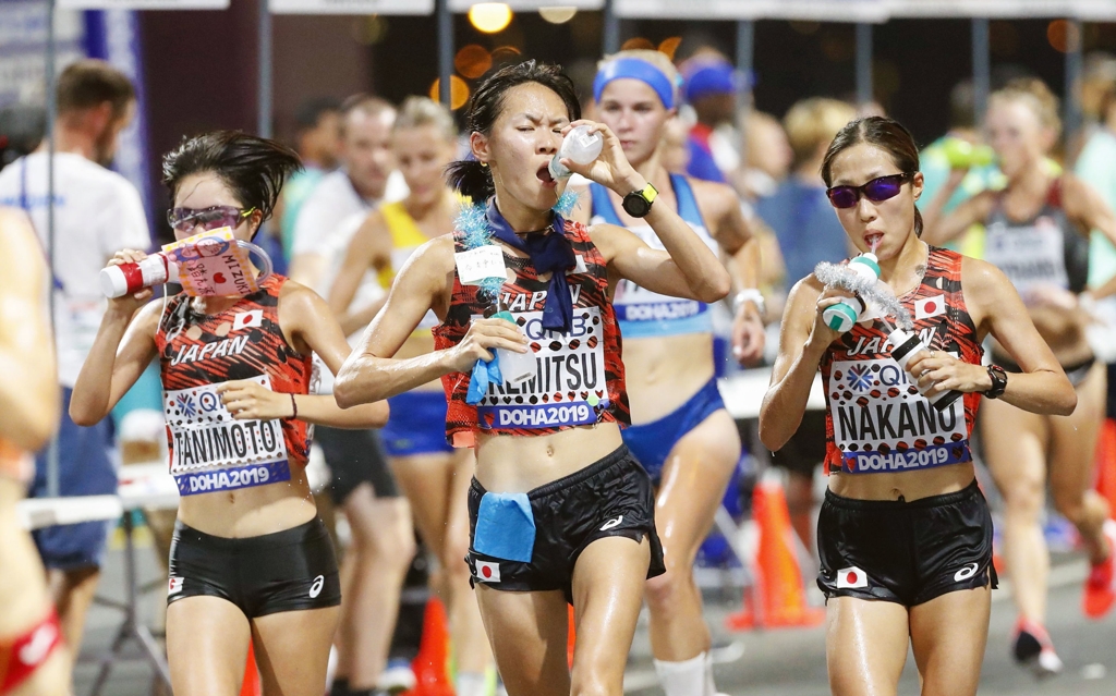 도하 세계육상대회 여자 마라톤에 참가한 일본 선수들이 물을 마시며 역주하고 있다
