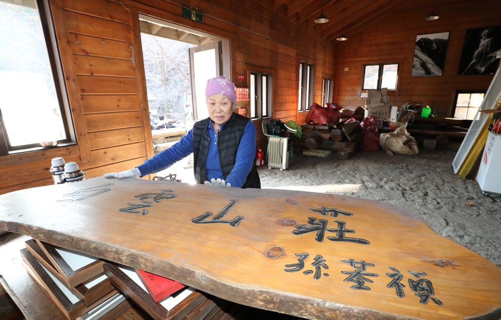 산장지기 김금자 할머니가 철거된 산장 현판을 보고 있다.