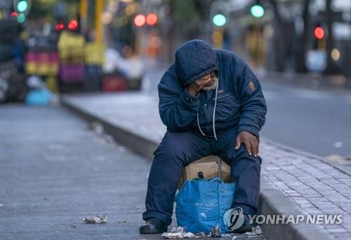 케이프타운 중심가서 한 노숙인이 봉쇄령 첫날인 27일 짐과 함께 앉아 있다. 