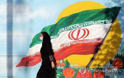 이란 국기 앞을 지나는 테헤란 시민