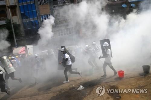 양곤에서 최루탄 속을 뛰어가고 있는 시위대