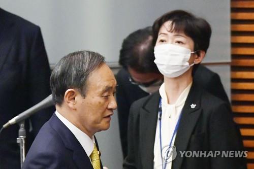 (도쿄 교도=연합뉴스) 작년 12월 4일 일본 총리관저에서 열린 기자회견 때 야마다 마키코(마스크) 일본 내각홍보관이 스가 요시히데(왼쪽) 총리 근처에 서 있다. 야마다는 스가의 장남인 세이고 씨로부터 접대를 받은 사실이 드러난 후 최근 사임했다.