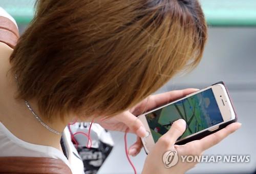 스마트폰으로 게임을 하며 이동하는 일본 젊은이