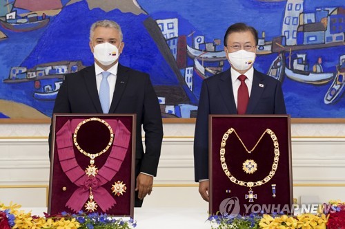 El presidente surcoreano, Moon Jae-in (dcha.), y el presidente colombiano, Iván Duque Márquez, posan para una foto tras el intercambio de medallas de honor, el 25 de agosto de 2021, en la oficina presidencial, Cheong Wa Dae, en Seúl.
