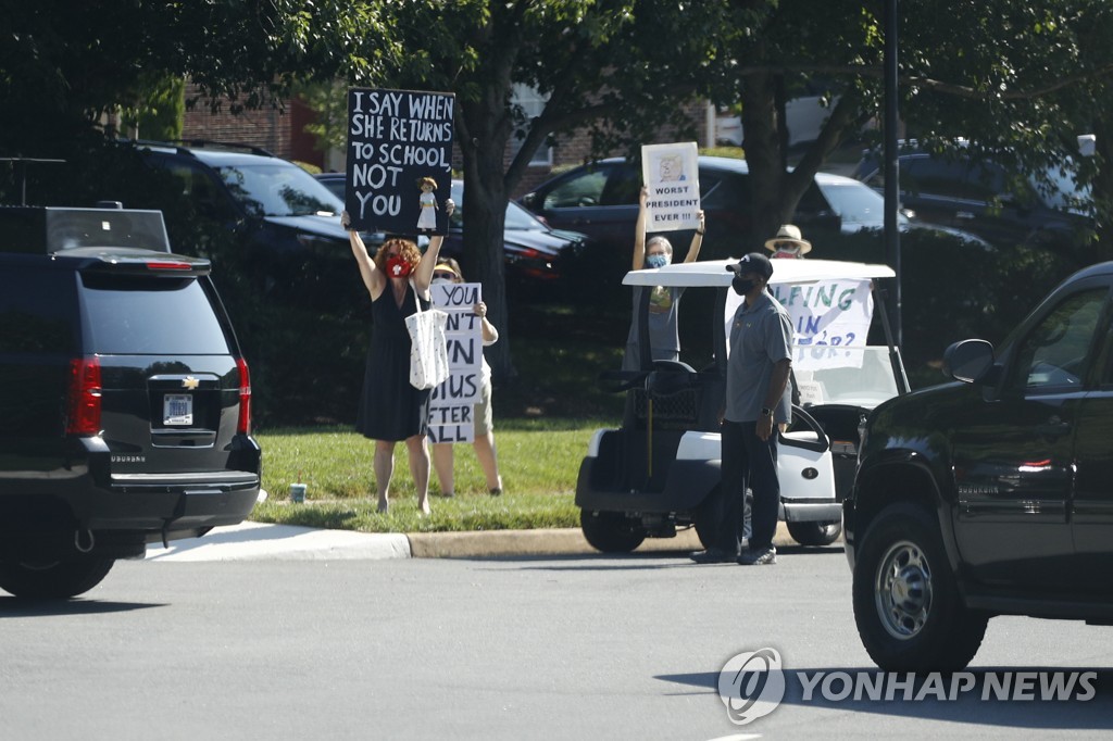 도널드 트럼프 미국 대통령의 차량 행렬이 도착한 버지니아주 스털링의 트럼프 내셔널 골프 클럽 밖에 시위대가 서있는 모습 [AP=연합뉴스]