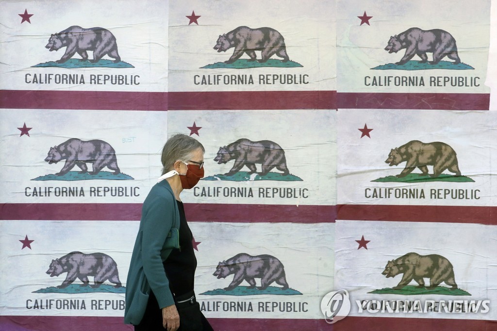캘리포니아 주 깃발이 그려진 광고판 옆을 지나는 샌프란시스코 주민