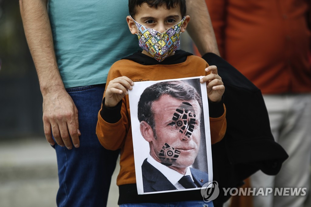 커지는 문화 갈등. 마크롱 대통령의 얼굴에 신발 자국을 찍은 사진을 들어 올린 터키 어린이[AP=연합뉴스]