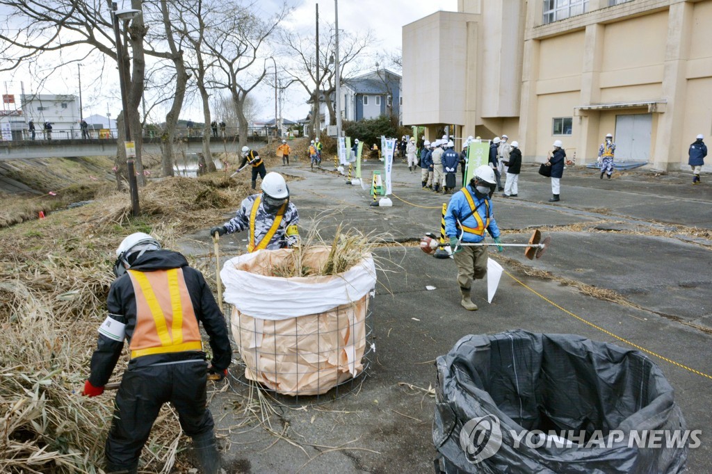 2017년 12월 25일 후쿠시마현 후타바마치에서 방사성 물질 오염 제거 작업이 진행 중이다. 작업자들이 풀 등을 베어 자루에 담고 있다. [교도=연합뉴스 자료사진]