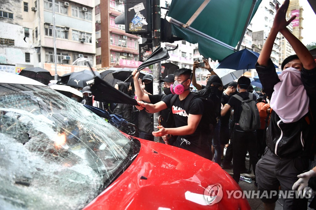 6일 홍콩에서 시위대가 시위 참가자들을 충돌한 택시를 파괴하고 있다. [AFP=연합뉴스]