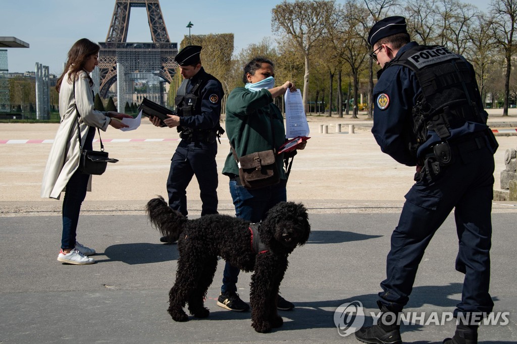 지난 7일 프랑스 파리 에펠탑 인근에서 전국 이동제한령 위반을 단속 중인 경찰관들이 시민들의 이동증명서를 검사하고 있다. [AFP=연합뉴스 자료사진]