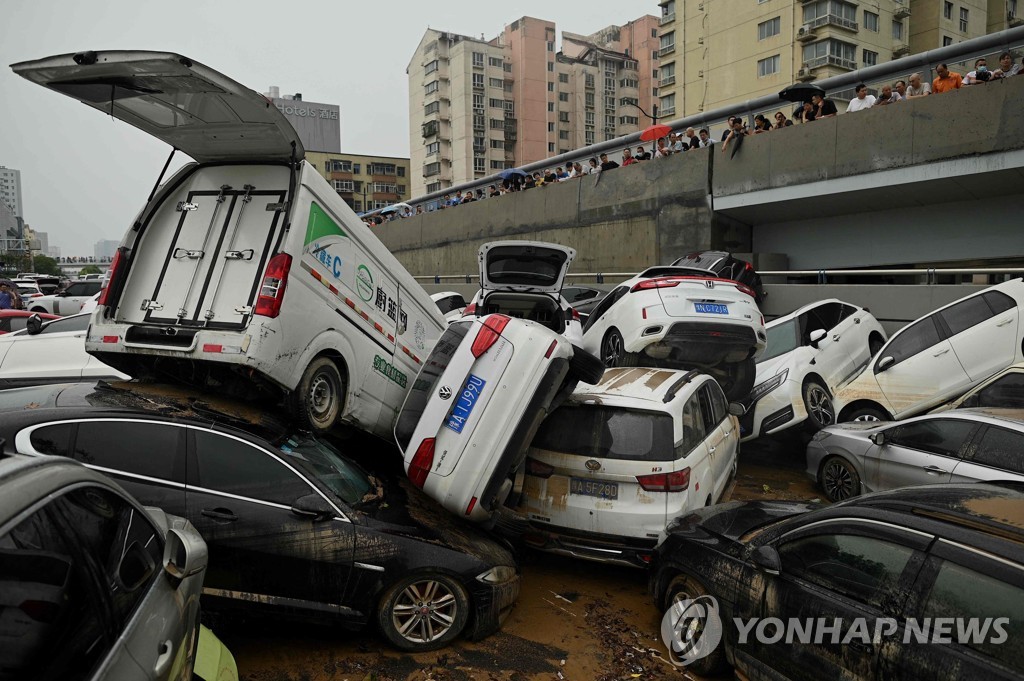 22일 허난성 정저우에서 주민들이 폭우로 겹겹이 쌓인 차량을 보고 있다. [AFP=연합뉴스]