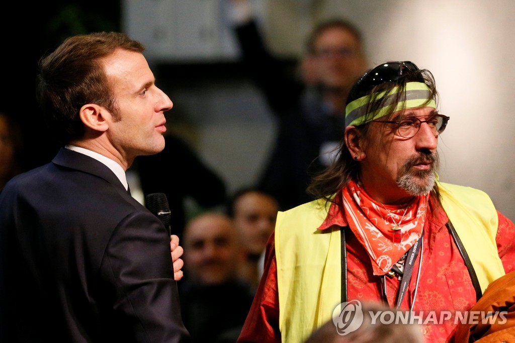 24일(현지시간) 사회적 대토론에 예고없이 참석해 마이크 잡은 에마뉘엘 마크롱 프랑스 대통령(왼쪽)과 '노란 조끼'를 입은 시민[로이터=연합뉴스]