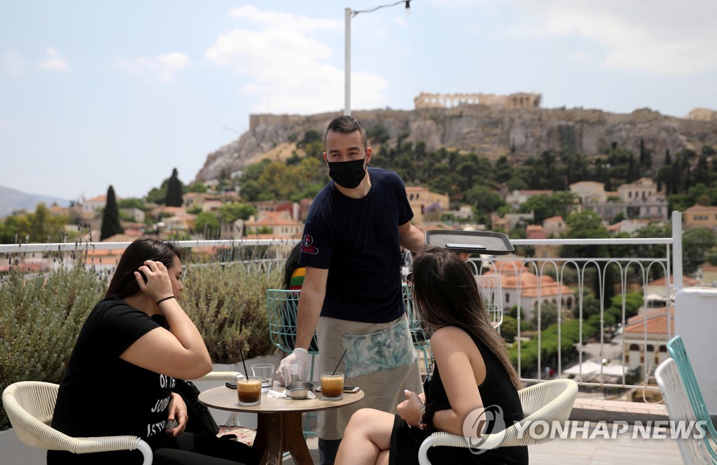 그리스 아테네의 한 음식점에서 마스크를 쓴 채 손님을 응대하는 직원. 2020.5.25. [로이터=연합뉴스]