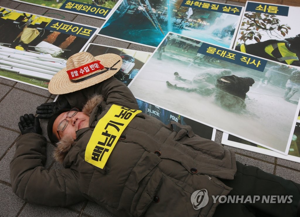2015년 12월 24일 오전 서울 서대문구 경찰청 앞에서 '민주노총 공안탄압 현황 발표 및 무더기 사법처리 규탄 기자회견'에서 한 참가자가 같은 해 11월 14일 서울 도심 집회에서 백남기씨가 경찰의 물대포에 맞고 쓰러진 모습을 재연하고 있다. <<연합뉴스 자료사진>>