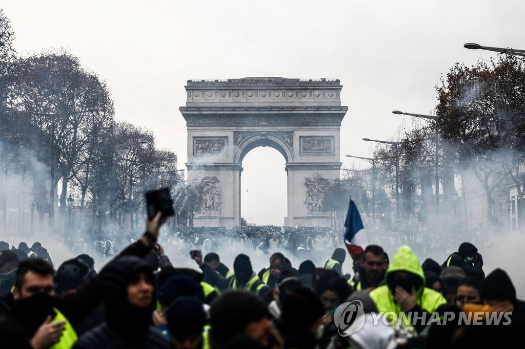 (파리 AFP=연합뉴스) 프랑스의 '노란조끼'(Gilets Jaunes) 시위대가 지난 8일(현지시간) 파리 개선문 앞에서 최루가스가 자욱한 가운데 시위를 벌이고 있다. 