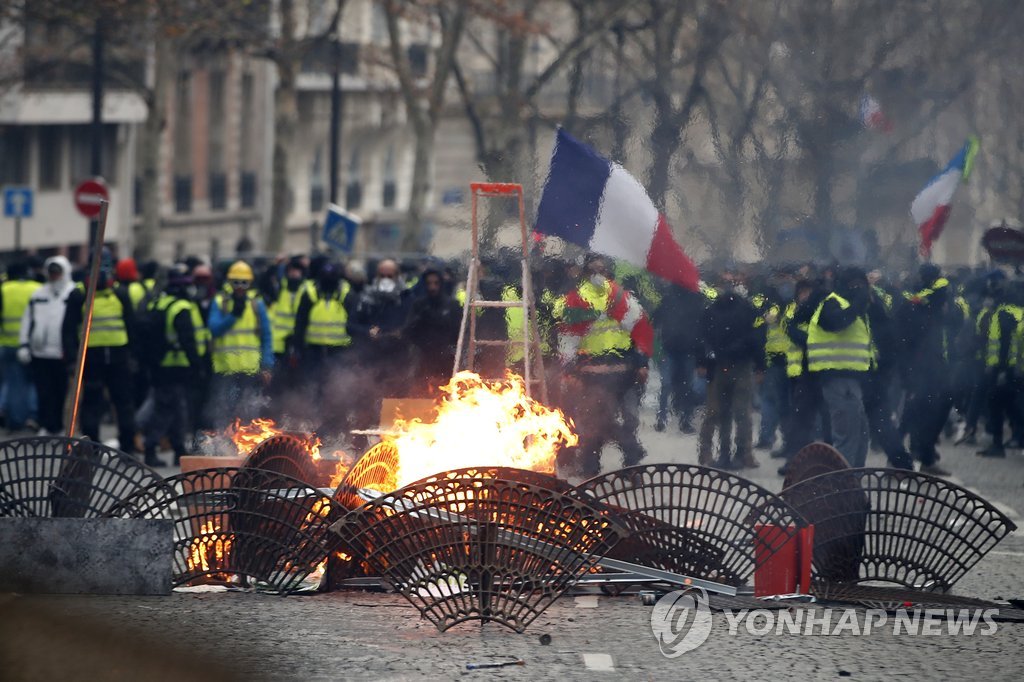프랑스 '노란조끼' 시위대가 지난 8일(현지시간) 파리 최대번화가인 샹젤리제 거리 인근에서 바리케이드를 세우고 불을 피운 채 경찰과 대치하고 있다. [EPA=연합뉴스]