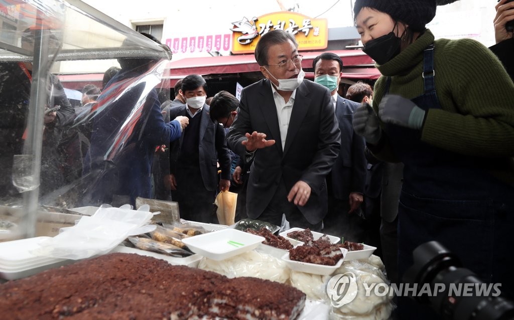 Pesident Moon Jae-in talks with a rice cake vendor at the Namdaemun Market in Seoul on Feb. 12, 2020. (Yonhap)