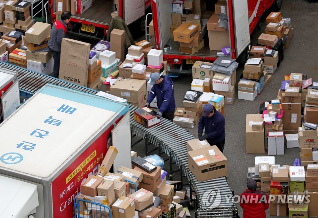 Workers handle parcels at a distribution center in Seoul on March 17, 2020, amid rising demand for delivery services. (Yonhap)