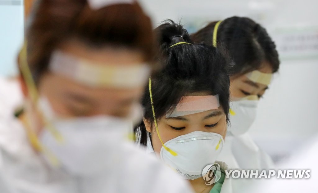 韓国南東部・大邱市の病院で、新型コロナウイルスによる感染症の患者を治療する医療従事者が、長時間のゴーグル着用による傷を防ぐために額にばんそうこうを貼っている＝１３日、大邱（聯合ニュース）
