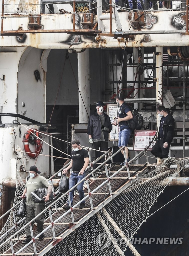 Crew members of a 7,733-ton Russian pelagic fishing boat get off the ship to be transported to Busan Medical Center in Busan on July 24, 2020. Of the 92 crewmen, 32 tested positive for COVID-19. (Yonhap)