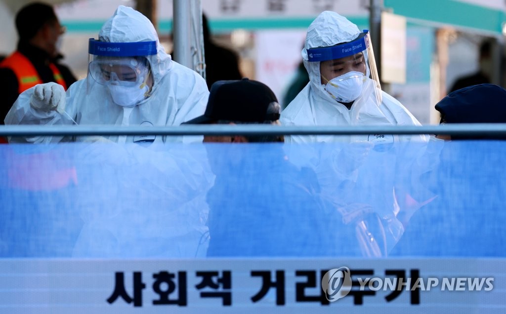 Medical workers carry out COVID-19 tests on visitors at a makeshift clinic in central Seoul on Dec. 16, 2020. (Yonhap)