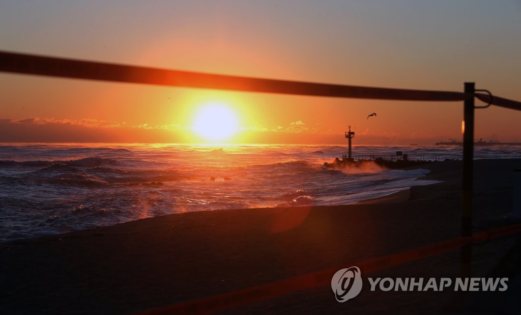해변 출입 통제선 너머로 뜨는 올해 마지막 일출
