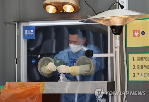 A health worker clad in a protective suit prepares to work at a makeshift virus testing clinic in Seoul on Jan. 19, 2021. (Yonhap)