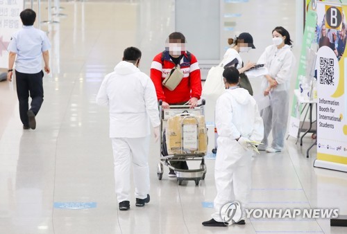 Des employés sanitaires guident les passagers à un terminal d'arrivée à l'aéroport international d'Incheon, le dimanche 5 septembre 2021.