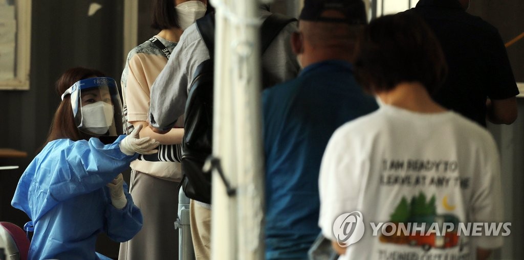 A health worker in a protective suit guides people at a makeshift COVID-19 testing clinic in Seoul on Sept. 17, 2021. (Yonhap)