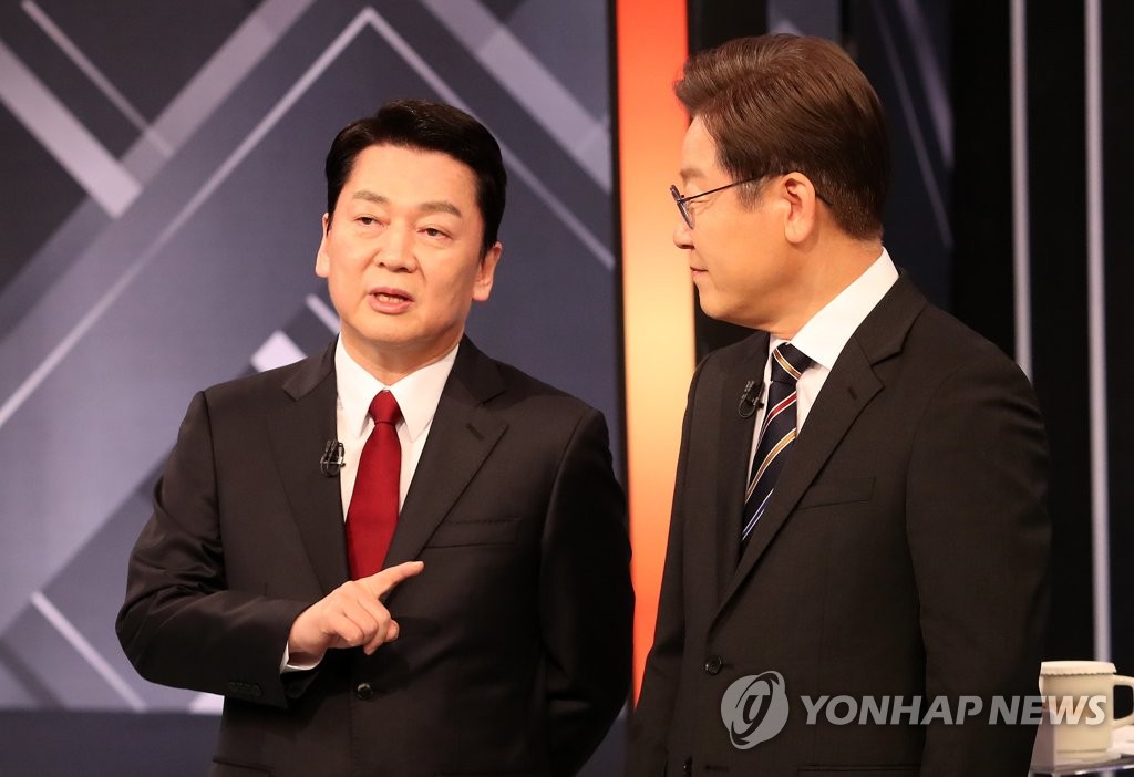 This file photo taken March 2, 2022, shows Lee Jae-myung (R), then presidential candidate of the Democratic Party, speaking with Ahn Cheol-soo, then presidential candidate of the People's Party, before a presidential debate in Seoul. (Yonhap)