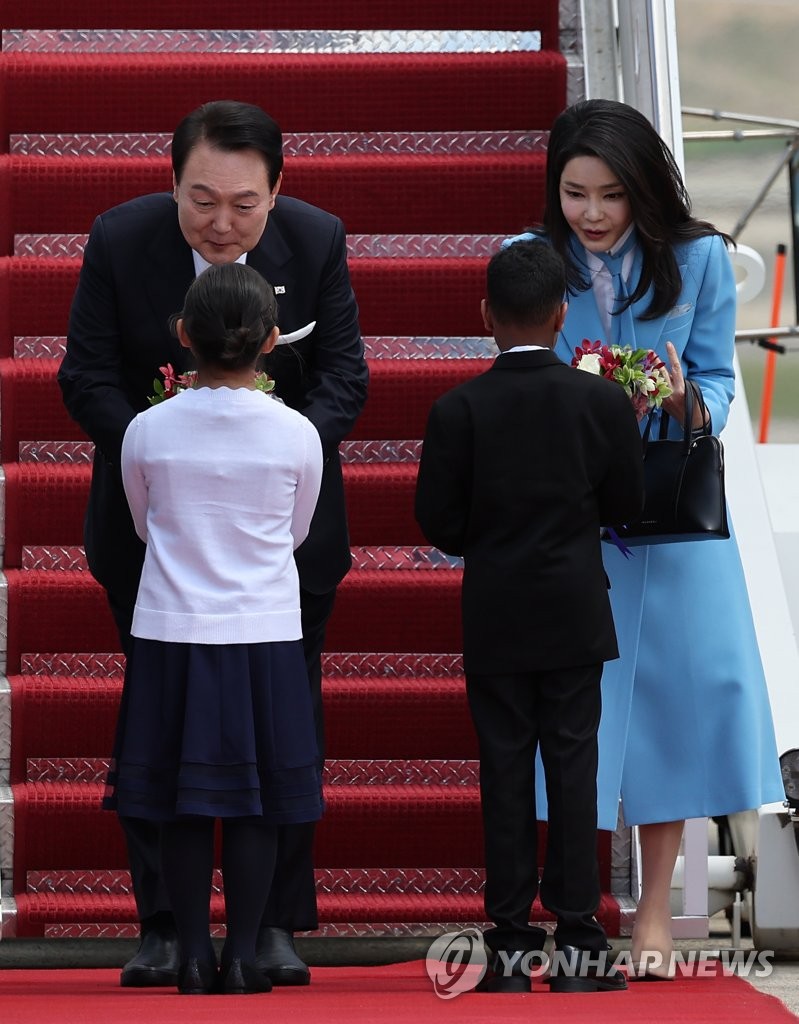 President Yoon Suk Yeol (L) and first lady Kim Keon Hee receive bouquets of flowers from children upon arrival at Joint Base Andrews, Maryland, on April 24, 2023. (Yonhap)