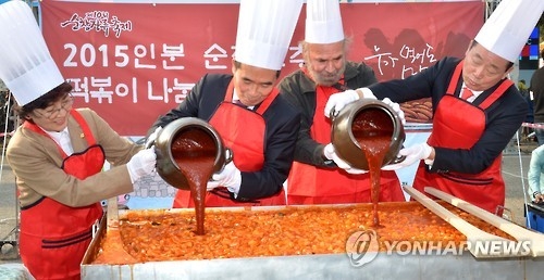 In this photo provided by the Sunchang County Office, participants of the "2016 Sunchang Fermented Soybean Product Festiva" make tteokbokki, a popular Korean snack food made from rice cake and red pepper paste, at Sunchang Traditional Gochujang Folk Village in Sunchang County, 364 kilometers south of Seoul, on Oct. 31, 2014. (Yonhap)
