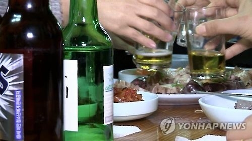 This undated photo captured from Yonhap News TV shows people toasting with beer and soju, a distilled beverage made of ethanol and water. (Yonhap) 