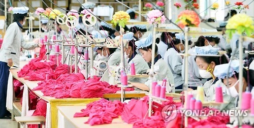 The file photo, taken in September 2013, shows dozens of North Korean employees working at a factory of a South Korean company in Kaesong, North Korea. (Yonhap)